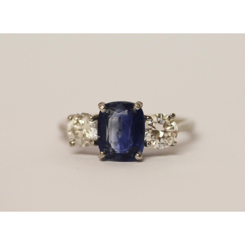 454 - A sapphire and diamond three stone ring, The central oval mixed cut sapphire claw set, flanked betwe... 