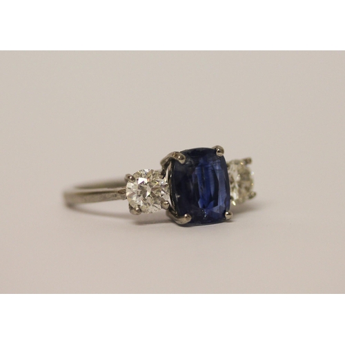 454 - A sapphire and diamond three stone ring, The central oval mixed cut sapphire claw set, flanked betwe... 