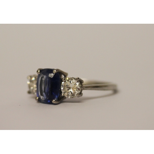 454 - A sapphire and diamond three stone ring, The central oval mixed cut sapphire claw set, flanked betwe... 