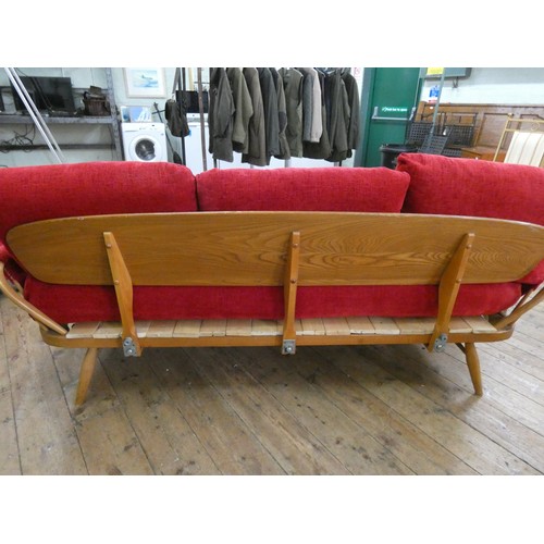 68 - An Ercol rounded back settee with loose red upholstered cushions, base has been repaired with wooden... 