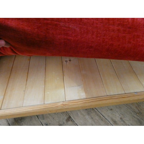 68 - An Ercol rounded back settee with loose red upholstered cushions, base has been repaired with wooden... 