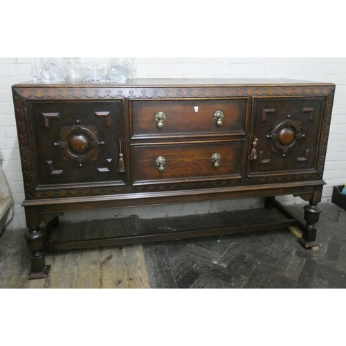 205 - A 1920's oak sideboard fitted two centre drawers and embossed carving to the doors, standing on bulb... 