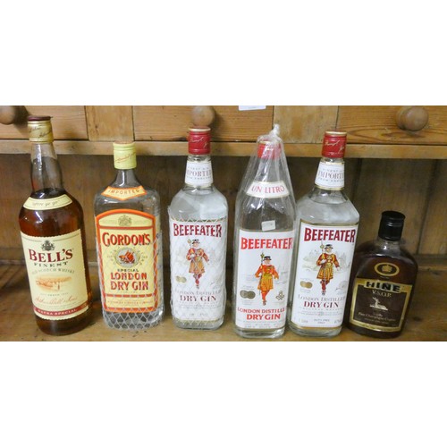 194 - Three bottles of Beefeater gin, a Gordons gin, bottle of Bell's whisky and a half bottle of Hine bra... 