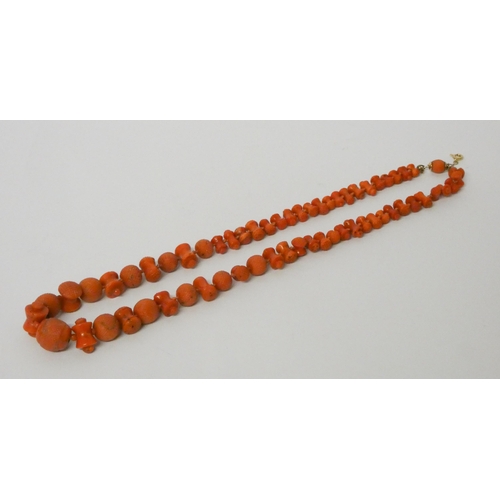 560 - A coral bead necklace, of graduated carved circular and bobbin shaped beads, 48cms long, to 9ct gold... 