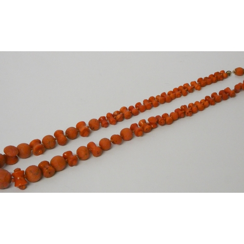 560 - A coral bead necklace, of graduated carved circular and bobbin shaped beads, 48cms long, to 9ct gold... 