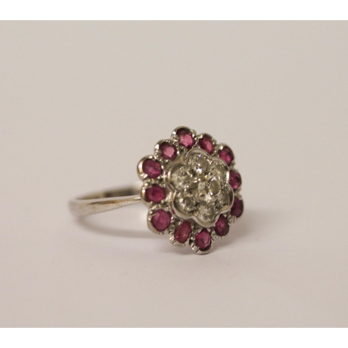 606 - A ruby and diamond flower shaped cluster ring, on 18ct and platinum band. Ring size K, weight 4.2g