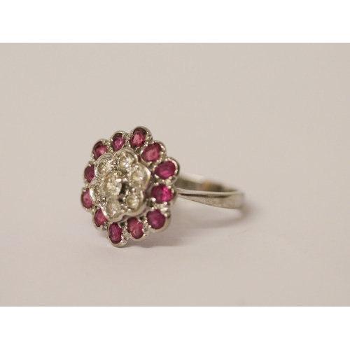 606 - A ruby and diamond flower shaped cluster ring, on 18ct and platinum band. Ring size K, weight 4.2g