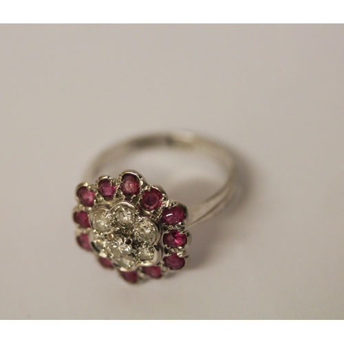 606 - A ruby and diamond flower shaped cluster ring, on 18ct and platinum band. Ring size K, weight 4.2g