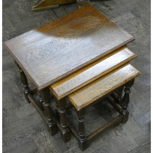 156 - An oak tea trolley fitted with cupboard and a nest of three oak coffee tables