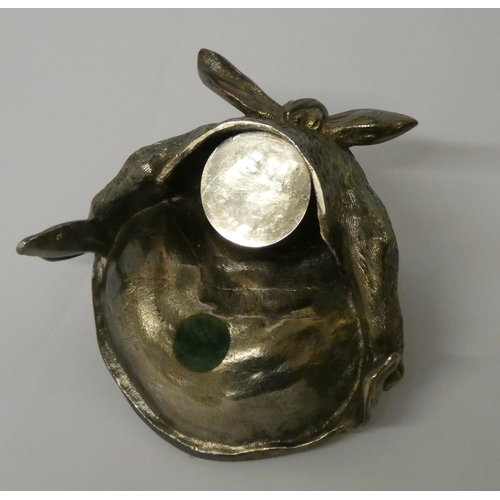 666 - A silver plated inkwell modelled as a cat with green glass eyes