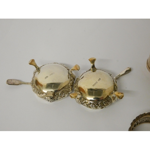 671 - A collection of five silver napkin rings and a pair of silver cauldron shaped salt cellars with blue... 