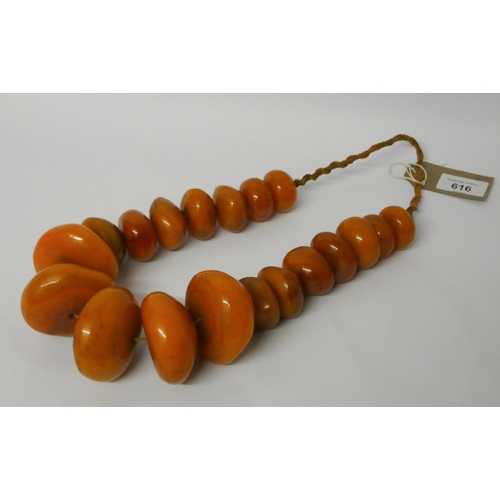 616 - A very large row of amber look beads, largest bead 6cms diameter