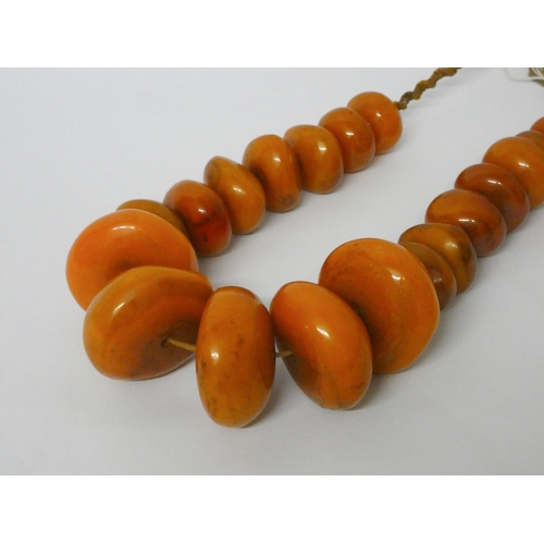 616 - A very large row of amber look beads, largest bead 6cms diameter