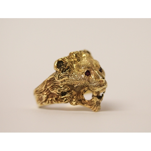 519 - A gents lion motif gold chunky ring, tests as 9ct gold with ruby eyes. Ring size U, 11.9g