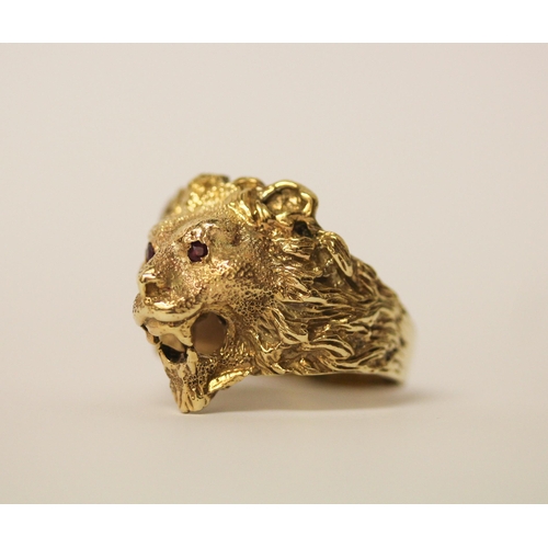 519 - A gents lion motif gold chunky ring, tests as 9ct gold with ruby eyes. Ring size U, 11.9g