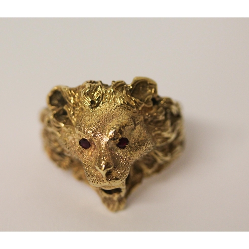 519 - A gents lion motif gold chunky ring, tests as 9ct gold with ruby eyes. Ring size U, 11.9g