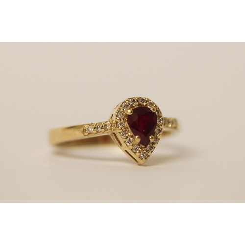 525 - A pear shaped ruby and diamond cluster ring, with diamond set shoulders on 14ct yellow gold band, ri... 