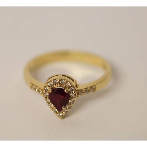 525 - A pear shaped ruby and diamond cluster ring, with diamond set shoulders on 14ct yellow gold band, ri... 