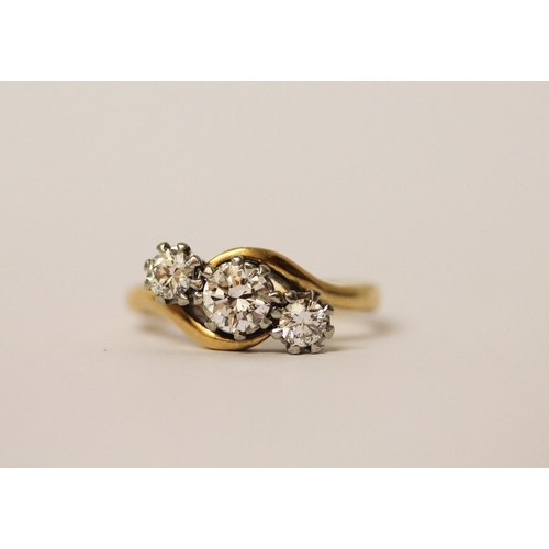 527 - A three stone diamond ring in a twist design, on 18ct yellow gold and platinum setting. Ring size N,... 