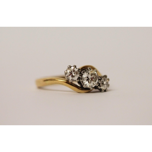 527 - A three stone diamond ring in a twist design, on 18ct yellow gold and platinum setting. Ring size N,... 