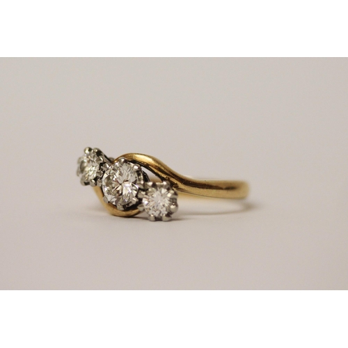 527 - A three stone diamond ring in a twist design, on 18ct yellow gold and platinum setting. Ring size N,... 