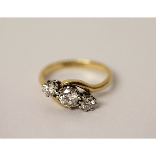 527 - A three stone diamond ring in a twist design, on 18ct yellow gold and platinum setting. Ring size N,... 