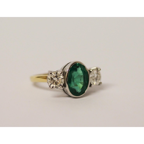 537 - An emerald and diamond three stone ring, the rub over set oval emerald estimated to weigh 2.4 carats... 