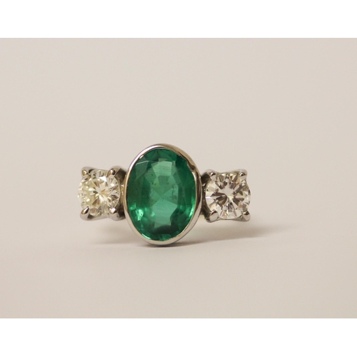 537 - An emerald and diamond three stone ring, the rub over set oval emerald estimated to weigh 2.4 carats... 