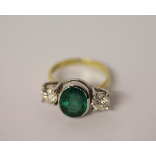 537 - An emerald and diamond three stone ring, the rub over set oval emerald estimated to weigh 2.4 carats... 