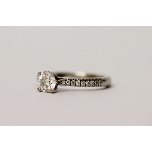 569 - A modern platinum and diamond ring, with a claw set brilliant diamond on diamond shoulders, hallmark... 