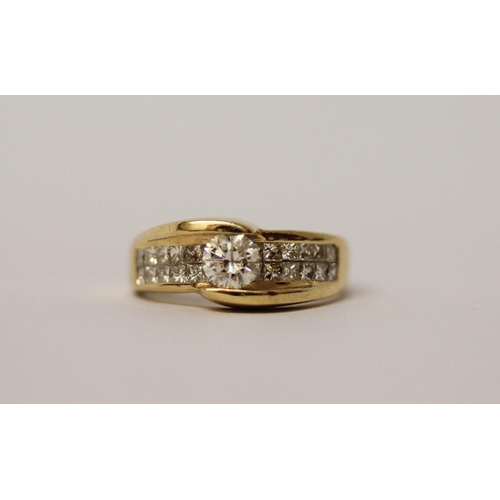 573 - An 18ct yellow gold diamond dress ring, with a central brilliant cut diamond on pave shoulders. Ring... 