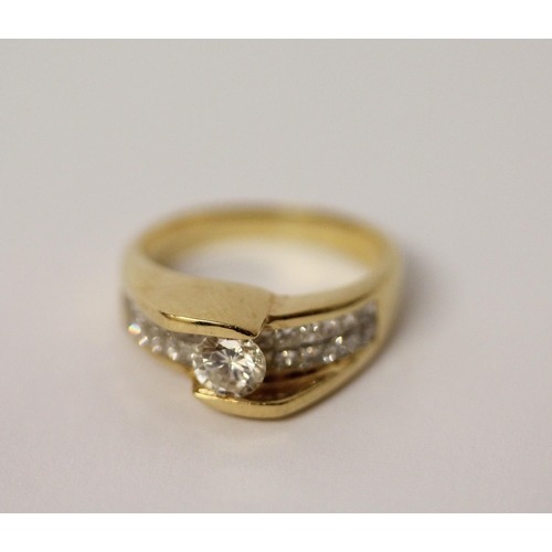 573 - An 18ct yellow gold diamond dress ring, with a central brilliant cut diamond on pave shoulders. Ring... 