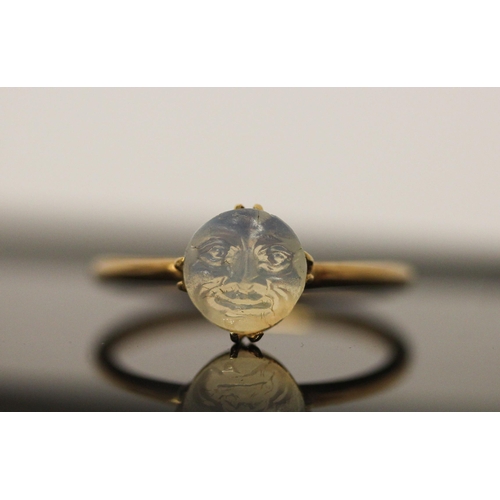 565 - Victorian carved moonstone Man in the Moon ring, on 18ct gold band. Ring size Q, Weight  2.6g