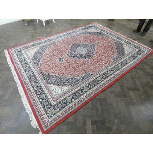 204 - A large red ground Persian design wool carpet. 11'3