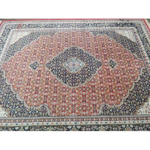 204 - A large red ground Persian design wool carpet. 11'3