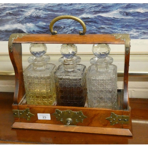 23 - An Edwardian oak and brass bound Tantalus containing three hobnail cut glass decanters