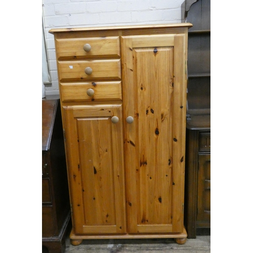 28 - A varnished pine small combination wardrobe, fitted hanging space, three drawers and a cupboard unde... 