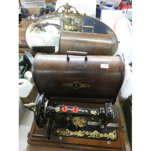 387 - A very old Singer sewing machine in wooden case and an old brass framed oval mirror