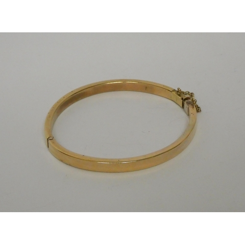 400 - A 9ct gold hinged bangle, snap clasp with safety chain fitted. Marked 375 to clasp. Weight 30.8g