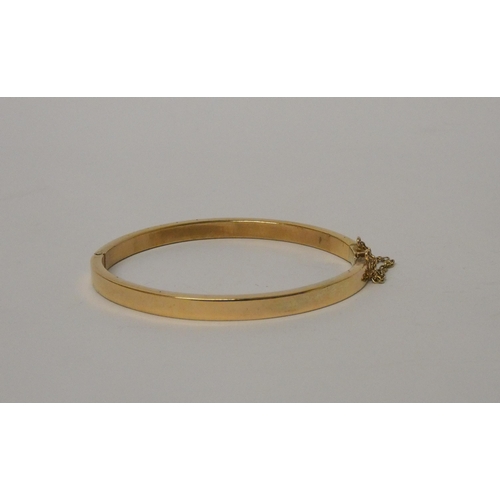 400 - A 9ct gold hinged bangle, snap clasp with safety chain fitted. Marked 375 to clasp. Weight 30.8g