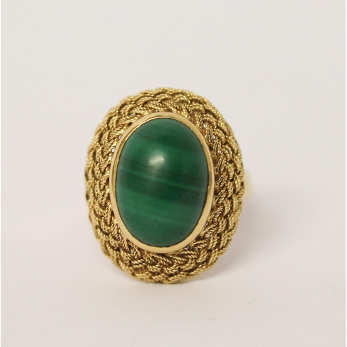 403 - A malachite dress ring, the oval stone in a raised filigree setting on 18ct yellow gold band. Marked... 