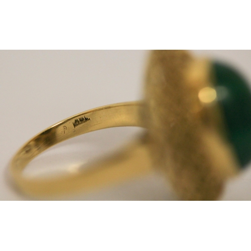 403 - A malachite dress ring, the oval stone in a raised filigree setting on 18ct yellow gold band. Marked... 