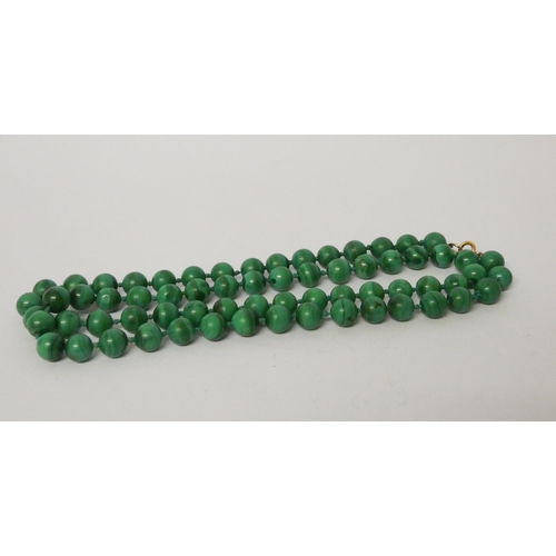 404 - A long uniform row of malachite beads, knotted silk, to yellow metal clasp, 70 cms long.