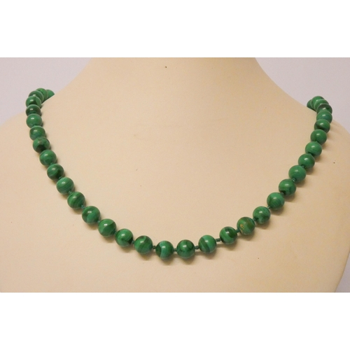 404 - A long uniform row of malachite beads, knotted silk, to yellow metal clasp, 70 cms long.