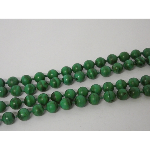 404 - A long uniform row of malachite beads, knotted silk, to yellow metal clasp, 70 cms long.