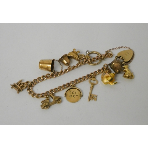 409 - A 9ct gold charm bracelet, set with numerous charms to a heart shaped padlock fastening. Gross weigh... 