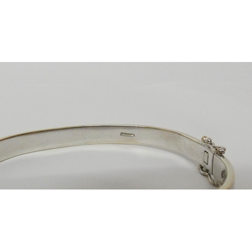 555 - A modern 9ct white gold diamond set hinged bangle, set with seven brilliant cut diamonds, invisible ... 