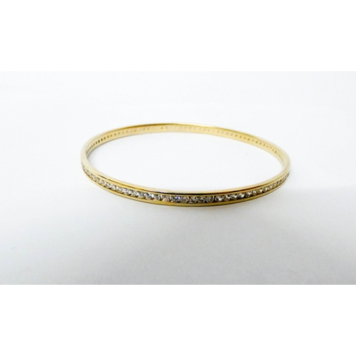 558 - A 9ct yellow gold bangle channel set with CZ stones, hallmarked, gross weight 10.6g