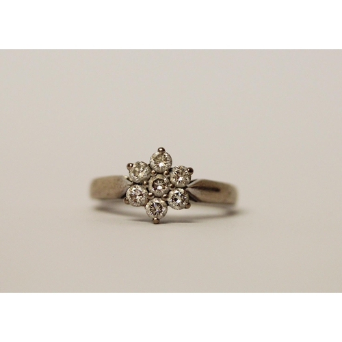 527 - A diamond daisy cluster ring, set seven diamonds on unmarked white precious metal band, ring size J,... 