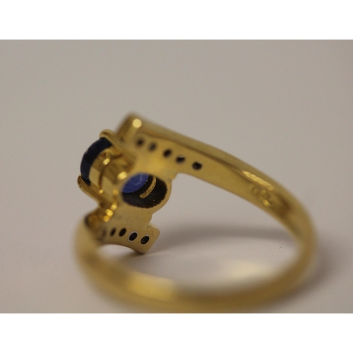 570 - A sapphire and diamond ring, in a twist cross over design, on  18ct yellow gold band, marked 750, ri... 